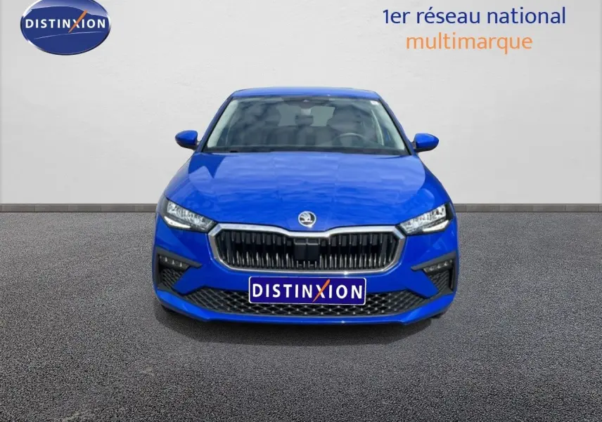 Vue avant d'une Skoda Scala 2025 bleu racing metal avec calandre noire et phares LED allumés.