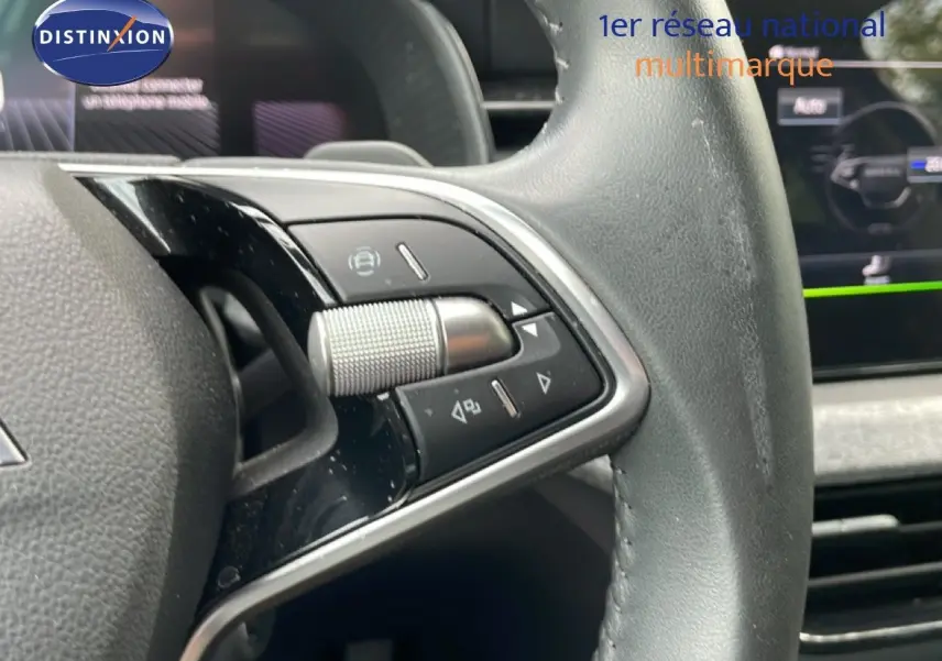 Gros plan sur les commandes du volant cuir noir de la Skoda Scala 2025, avec molette et boutons multifonctions.