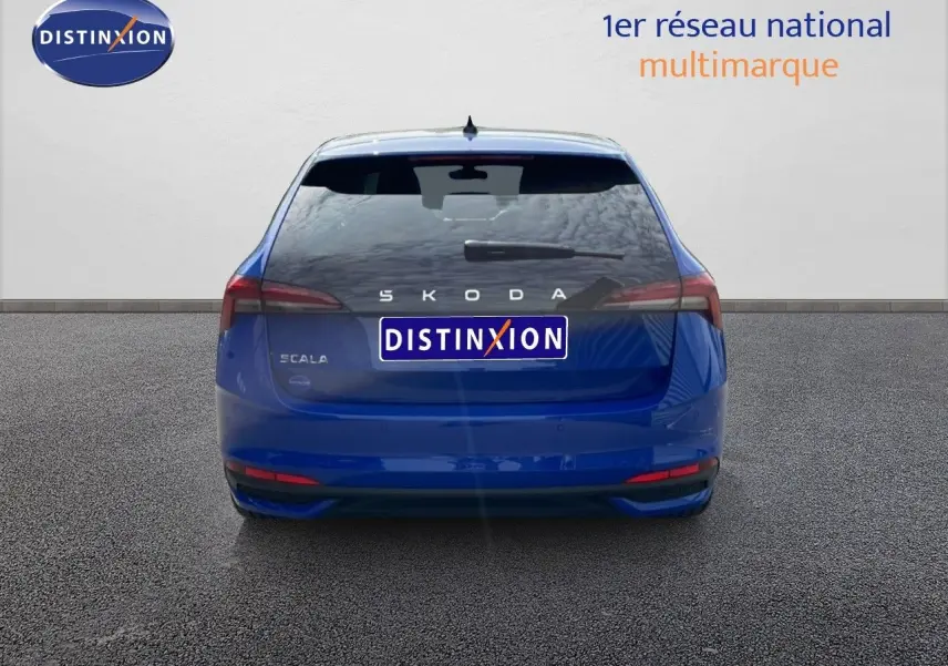Vue arrière d'une Skoda Scala 2025 en bleu racing metal, avec feux arrière étirés et logo distinctif au centre.