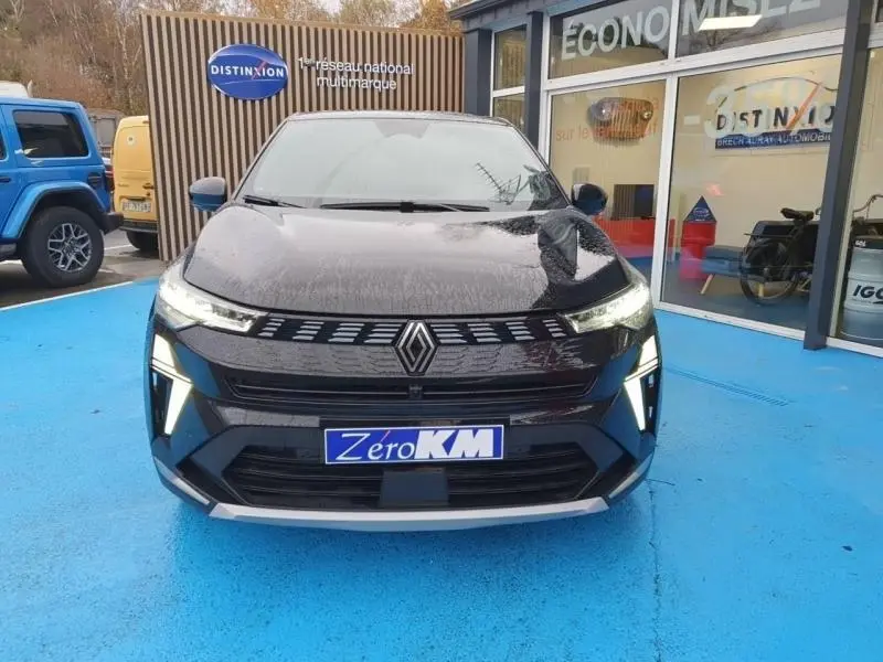 Vue avant d'un Renault Symbioz noir étoilé avec feux LED allumés sur un sol bleu devant un showroom.