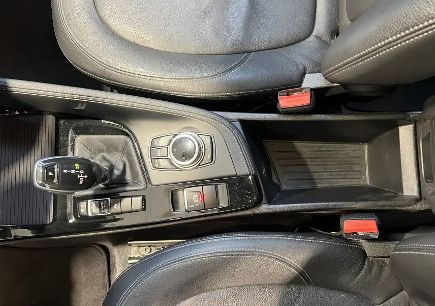 Vue plongeante sur la console centrale noire du BMW X1 F48 2017 avec levier de vitesse et commandes intégrées.