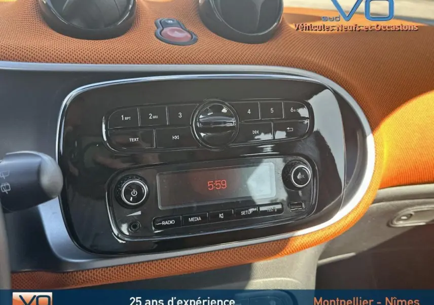 Tableau de bord orange et noir de la Smart Forfour 2015, avec commandes radio et affichage digital à 5:59.