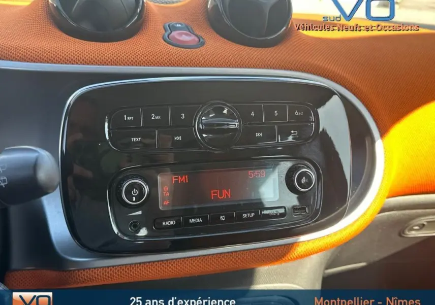 Tableau de bord orange et noir de la Smart Forfour 2015 avec autoradio affichant la station FM1 FUN.