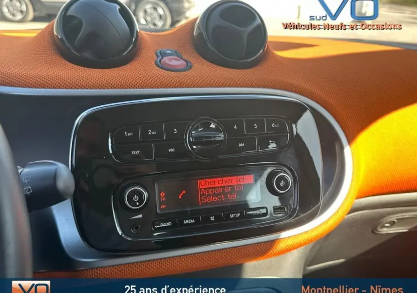 Tableau de bord orange vif de la Smart Forfour 2015 avec console centrale noire et commandes radio visibles.
