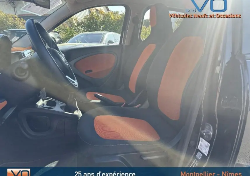 Intérieur de la Smart Forfour noir, vue côté gauche montrant les sièges bi-color orange et noir et le volant multifonctions.