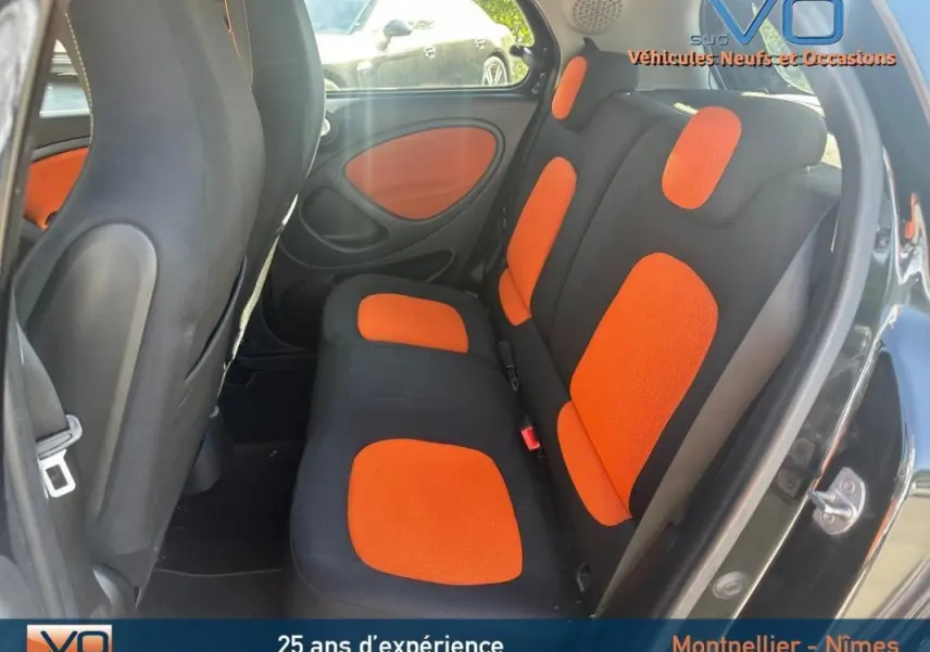 Vue intérieure arrière droite de la Smart Forfour noire 2015 avec sièges noirs et orange et panneaux de porte assortis.