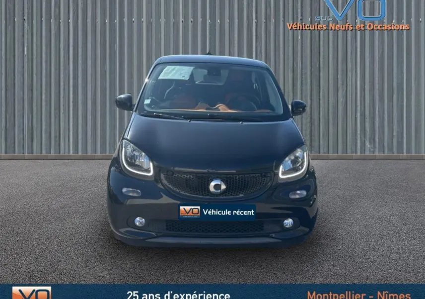 Vue avant d'une Smart Forfour noire de 2015 avec phares allumés et logo centré sur une façade métallique.