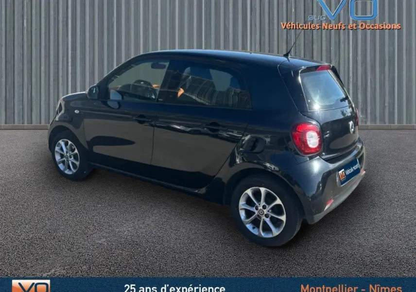 Vue 3/4 arrière droite d'une Smart Forfour noire de 2015, compacte avec feux arrière arrondis et jantes argentées.