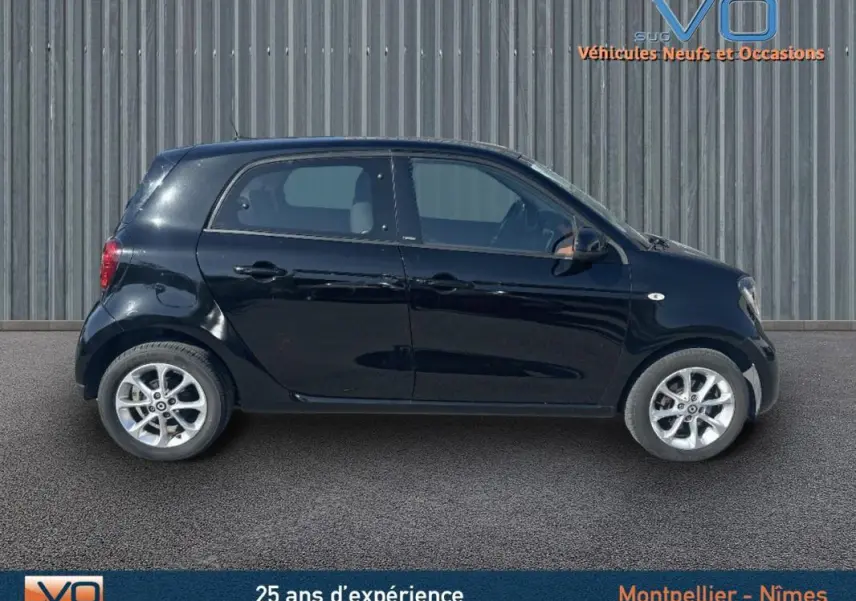 Vue latérale droite d'une Smart Forfour noire de 2015, compacte et élégante sur fond industriel.