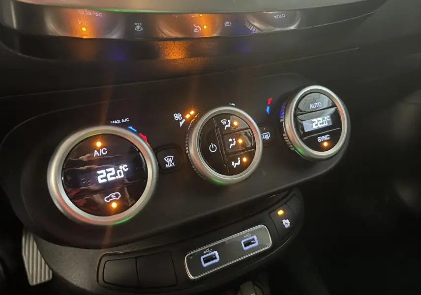 Vue rapprochée des commandes de climatisation automatique bi-zone et des ports USB arrière dans le Fiat 500X bleu 2024.
