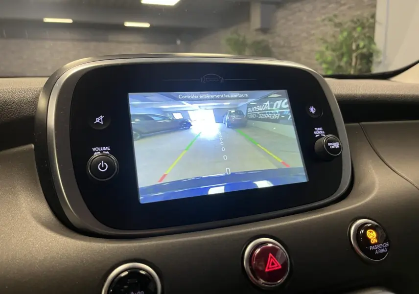 Écran central de la Fiat 500X bleu montrant la caméra de recul avec guidage de trajectoire en intérieur.