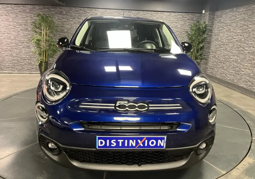 Vue frontale d'une Fiat 500X 2024 bleu métallisé avec phares LED ronds et calandre chromée distinctive.