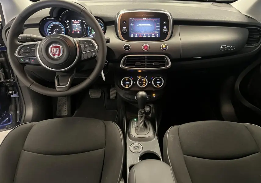 Intérieur de la Fiat 500X 2024 vu de face, avec tableau de bord gris titane et écran tactile central allumé.