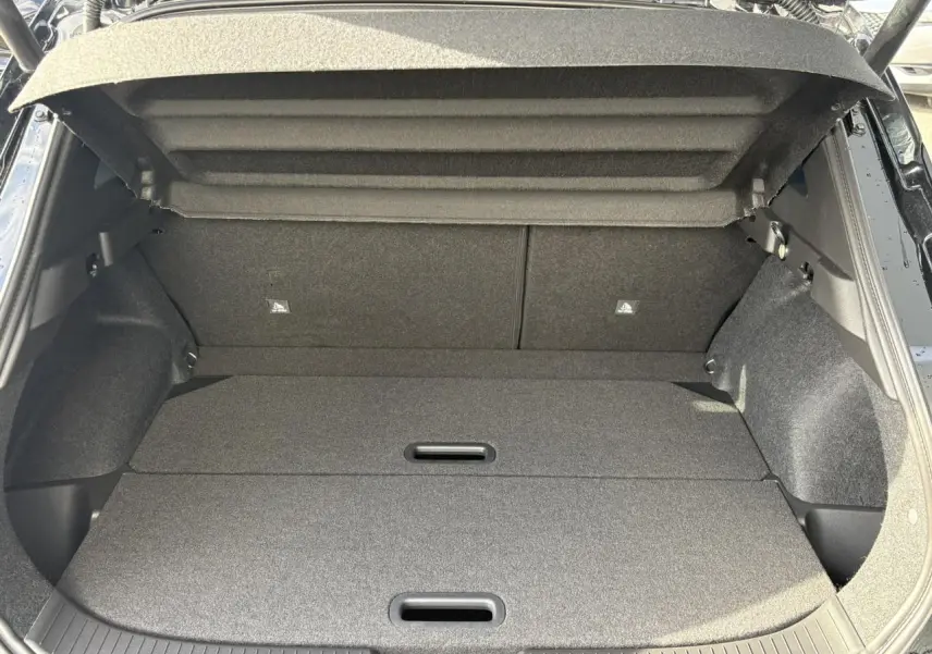 Vue plongeante sur le coffre noir ouvert du Nissan Qashqai 2025, montrant le plancher modulable et l'habillage intérieur.
