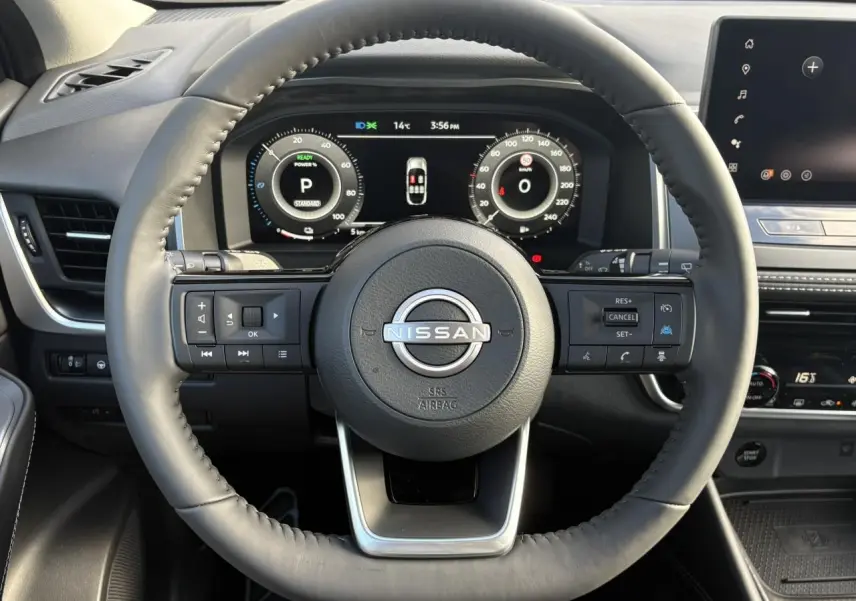 Vue intérieure centrée sur le volant cuir noir du Nissan Qashqai 2025 avec tableau de bord numérique et commandes intégrées.