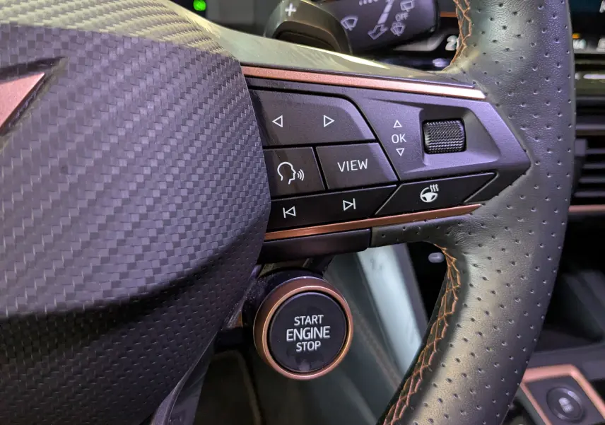 Gros plan sur le volant perforé noir de la CUPRA LEON ST 2025 avec boutons multifonctions et bouton Start Engine Stop.