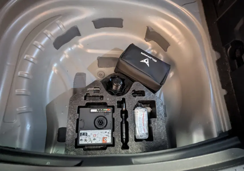 Vue plongeante sur le coffre ouvert d'une CUPRA Leon ST gris magnetic, montrant le rangement du kit de réparation pneus.