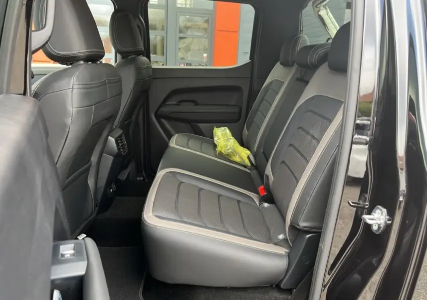 Vue intérieure côté droit sur les sièges arrière en cuir noir et tissu gris du Volkswagen Amarok Simple Cabine noir.