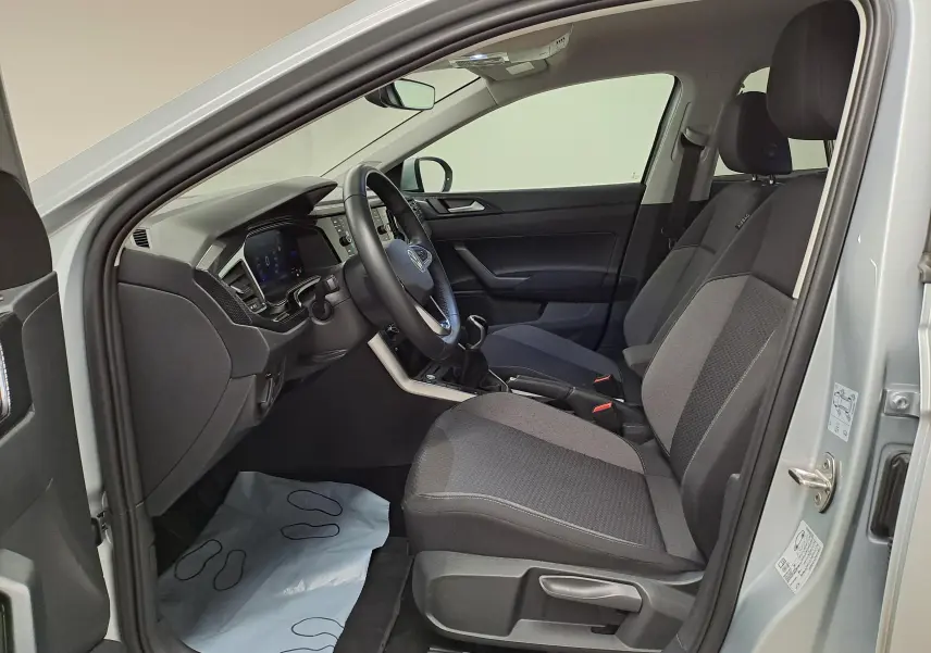 Vue intérieure côté conducteur du Volkswagen Taigo 2025 en Reflet d'argent, sièges tissu gris et tableau de bord moderne.
