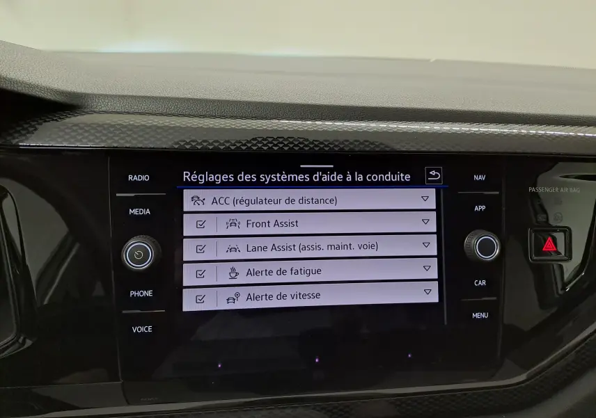Écran tactile central du Volkswagen Taigo 2025 affichant les réglages des aides à la conduite, entouré de boutons noirs.