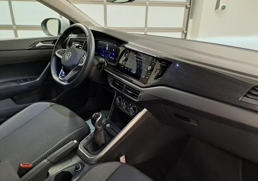 Vue intérieure côté conducteur du Volkswagen Taigo 2025, tableau de bord moderne avec écran tactile et levier de vitesses manuel.