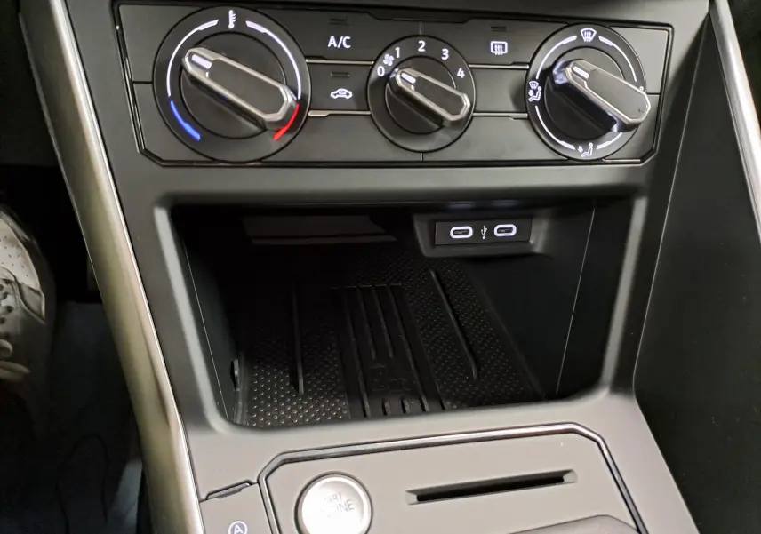 Gros plan sur la console centrale noire du Volkswagen Taigo 2025 avec commandes de climatisation et ports USB.