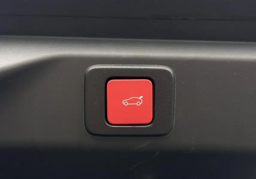Bouton rouge d'ouverture électrique du hayon sur Peugeot 3008 Hybrid 145 e-DSC6 GT, intérieur coffre noir.