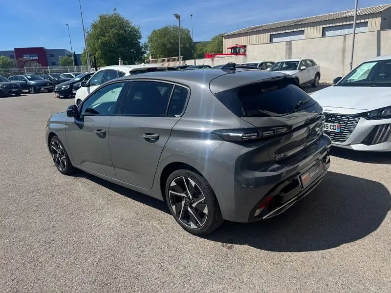 Peugeot 308 Hybrid gris vue 3/4 arrière droit, jantes alliage 17 pouces et vitres teintées.