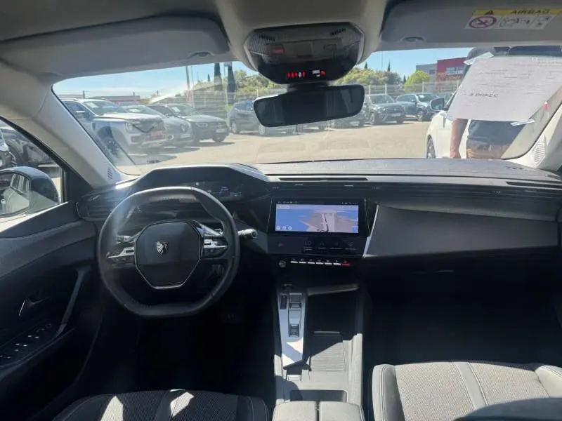 Vue intérieure avant de la Peugeot 308 Hybrid 145 gris, avec tableau de bord numérique et écran tactile central.