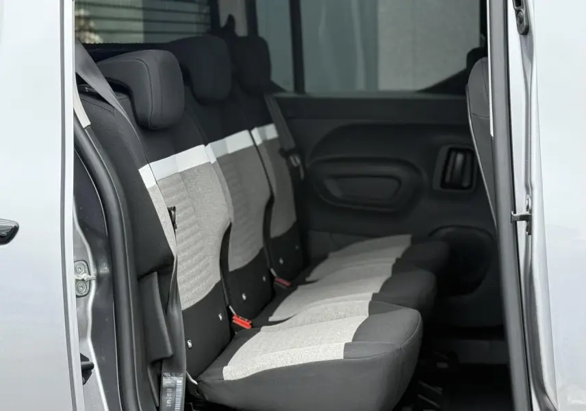 Vue latérale intérieure sur les trois sièges arrière gris clair et foncé du Citroën Berlingo Multispace 2026 avec porte coulissante ouverte.