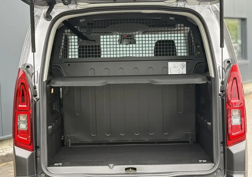 Vue arrière ouverte du Citroën Berlingo Multispace gris acier, montrant le coffre vide et la grille de séparation intérieure.