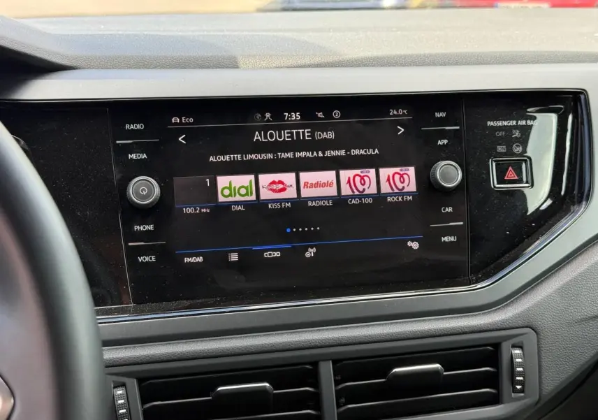 Vue rapprochée de l'écran tactile central noir du Volkswagen Taigo gris, affichant les stations radio numériques.
