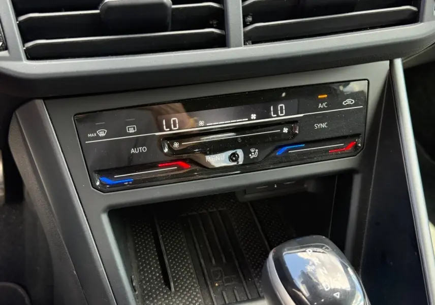 Gros plan sur la console centrale du Volkswagen Taigo gris, montrant la climatisation bi-zone et le levier de vitesses automatique.