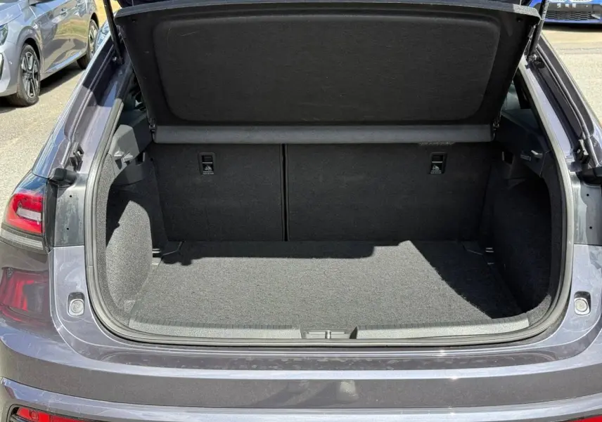 Coffre ouvert vu de l'arrière d'un Volkswagen Taigo gris 2025, montrant l'espace de chargement vide et la tablette cache-bagages relevée.