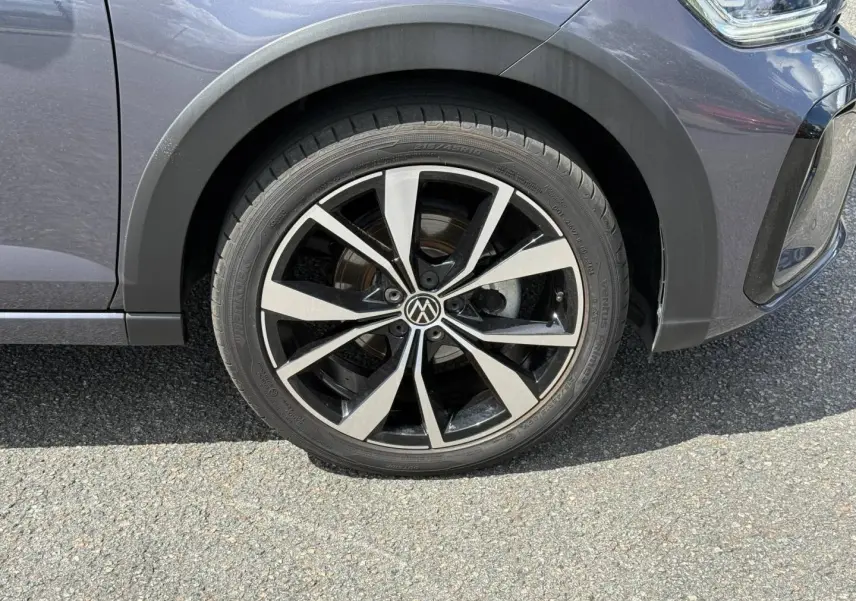 Gros plan sur la roue avant droite avec jante alliage bicolore du Volkswagen Taigo gris Ascot 2025.