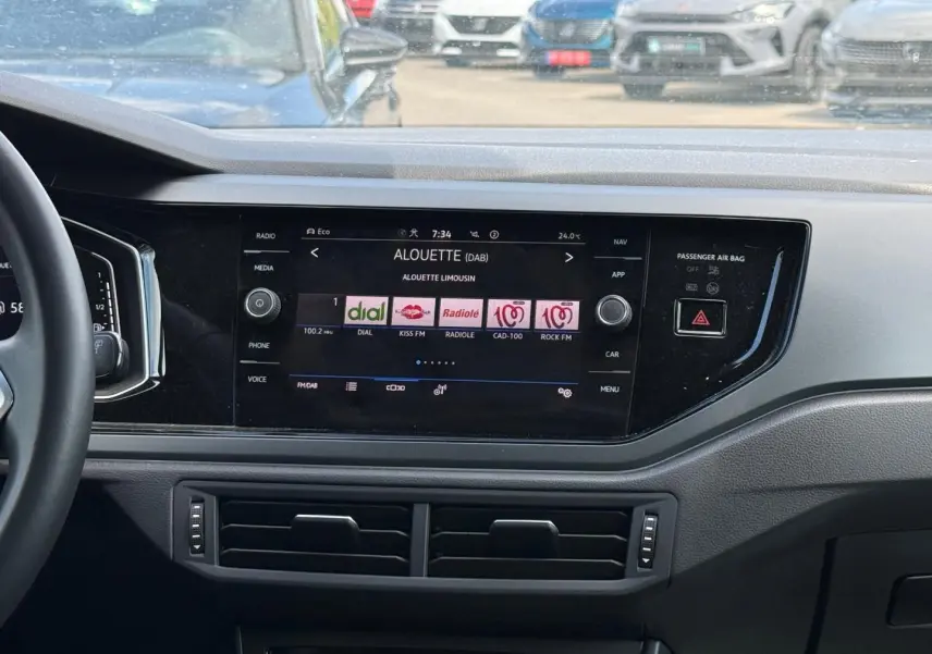 Tableau de bord du Volkswagen Taigo 2025 avec écran tactile central affichant des stations radio, volant partiel à gauche visible.