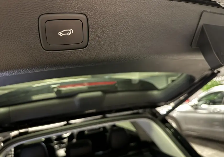 Bouton d'ouverture électrique du hayon sur le bord intérieur du coffre d'un MG MOTOR EHS noir vu de l'arrière ouvert.