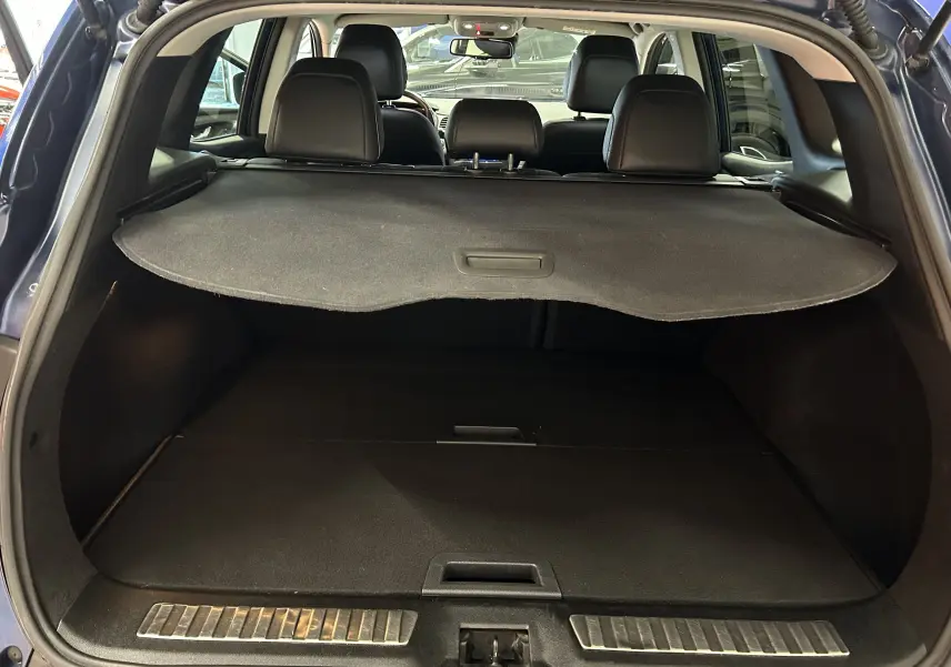 Coffre ouvert d'un Renault Kadjar bleu 2017, montrant la plage arrière et les sièges noirs en arrière-plan.