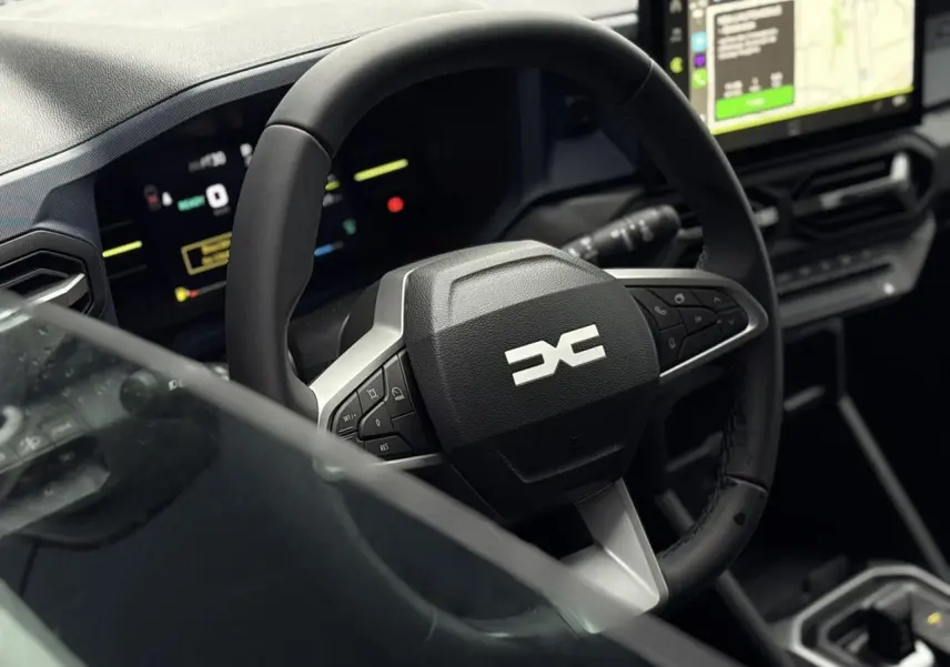 Vue rapprochée du volant noir et du tableau de bord digital du Dacia Duster 1.6 Hybrid 140 Journey 2025.