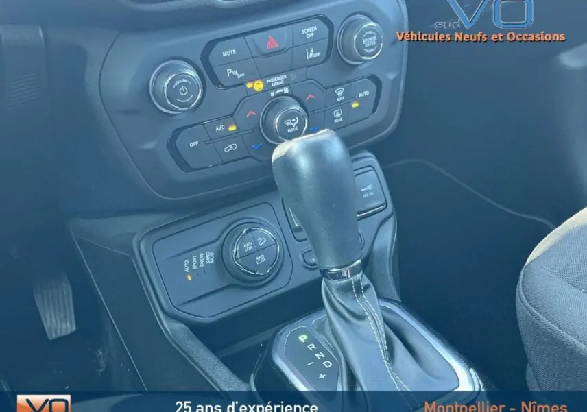 Gros plan sur la console centrale et levier de vitesse automatique du Jeep Renegade gris foncé, avec commandes climatisation et modes de conduite visibles.