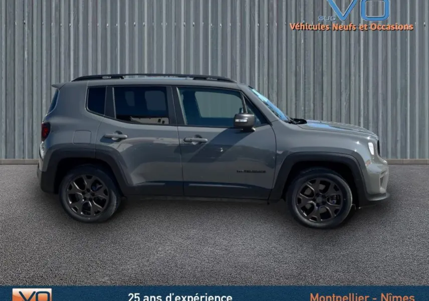 Jeep Renegade gris foncé vu de profil côté gauche, avec barres de toit et jantes alliage 18 pouces.