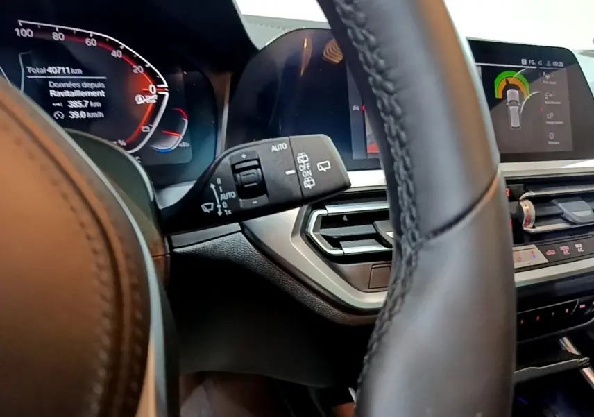 Gros plan sur le tableau de bord digital et le volant cuir noir d'une BMW Série 3 318i 2022 avec affichage multifonctions.