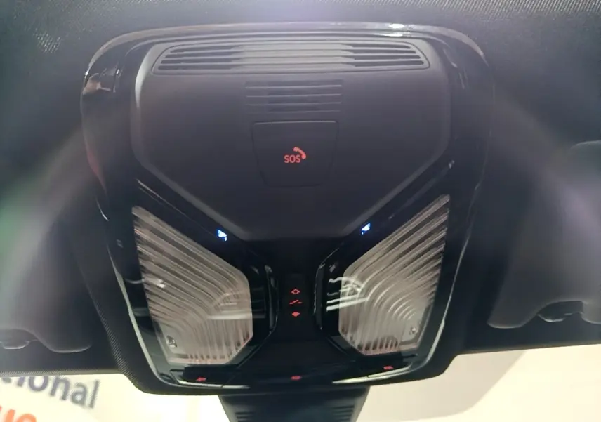 Vue en contre-plongée du plafonnier noir avec bouton SOS et éclairages LED intérieurs d'une BMW Série 3 noire 2022.