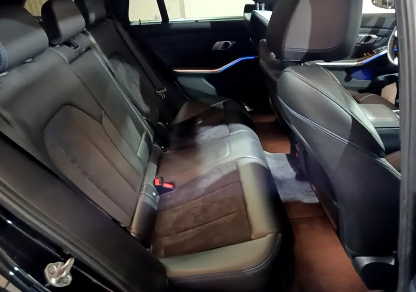 Vue intérieure côté droit sur la banquette arrière en cuir noir et alcantara de la BMW Série 3 318i M Sport 2022.