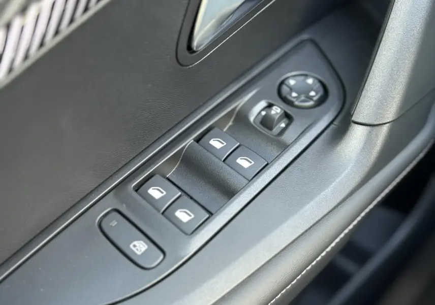 Gros plan sur les commandes des vitres électriques et rétroviseurs côté conducteur du Peugeot 2008 Hybrid gris Artense.