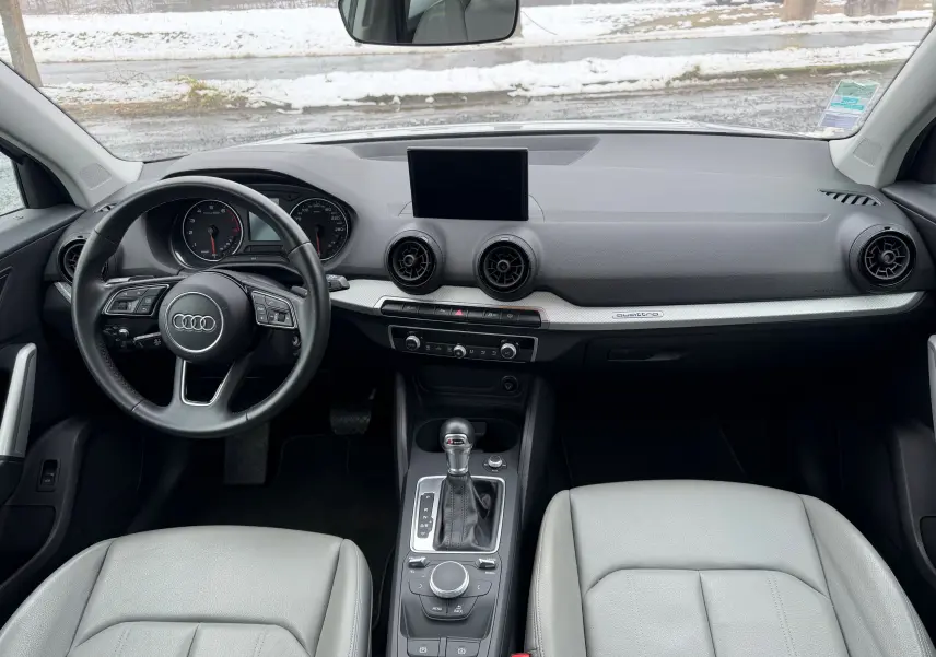 Vue intérieure avant de l'Audi Q2 2017, tableau de bord gris avec volant multifonction et sellerie similicuir gris clair.