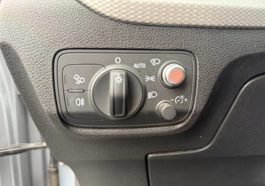 Gros plan sur la commande des phares et réglages lumineux dans l'habitacle de l'Audi Q2 gris aluminium.