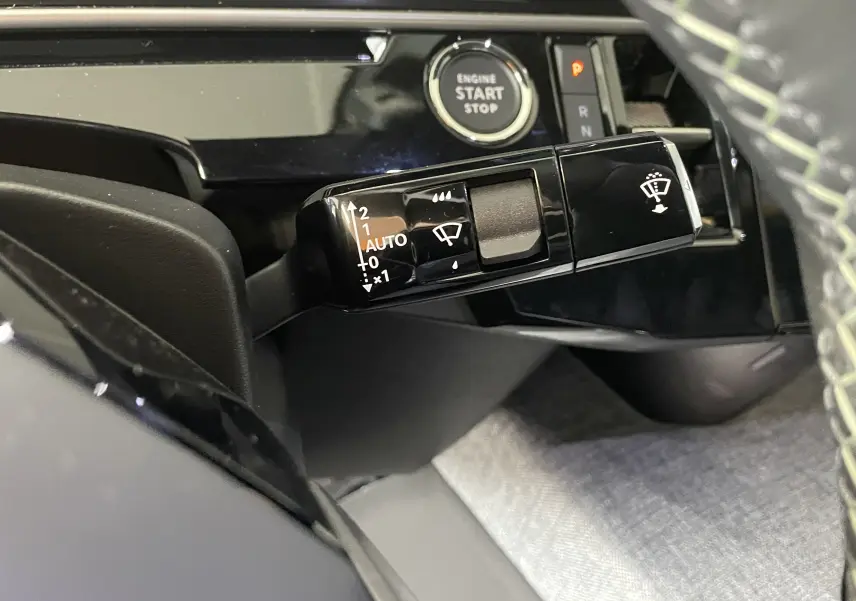 Gros plan sur la commande de l’essuie-glace à gauche du volant dans l’habitacle noir du Peugeot 3008 Hybrid 2026.