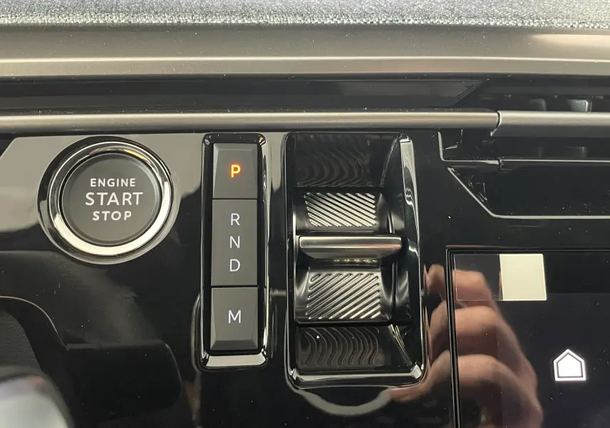 Gros plan sur la console centrale noire du Peugeot 3008 Hybrid 2026, avec bouton start/stop et sélecteur de vitesses électronique.