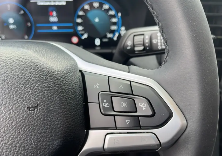 Gros plan sur le volant cuir multifonctions noir du Volkswagen Amarok V6 240 BVA10 Aventura avec commandes intégrées.